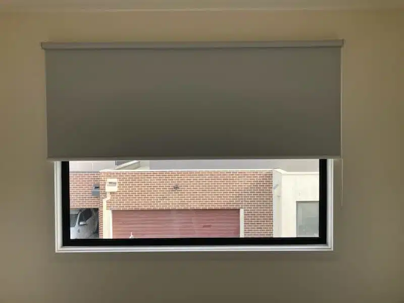 Grey roller blind partially lowered over a window