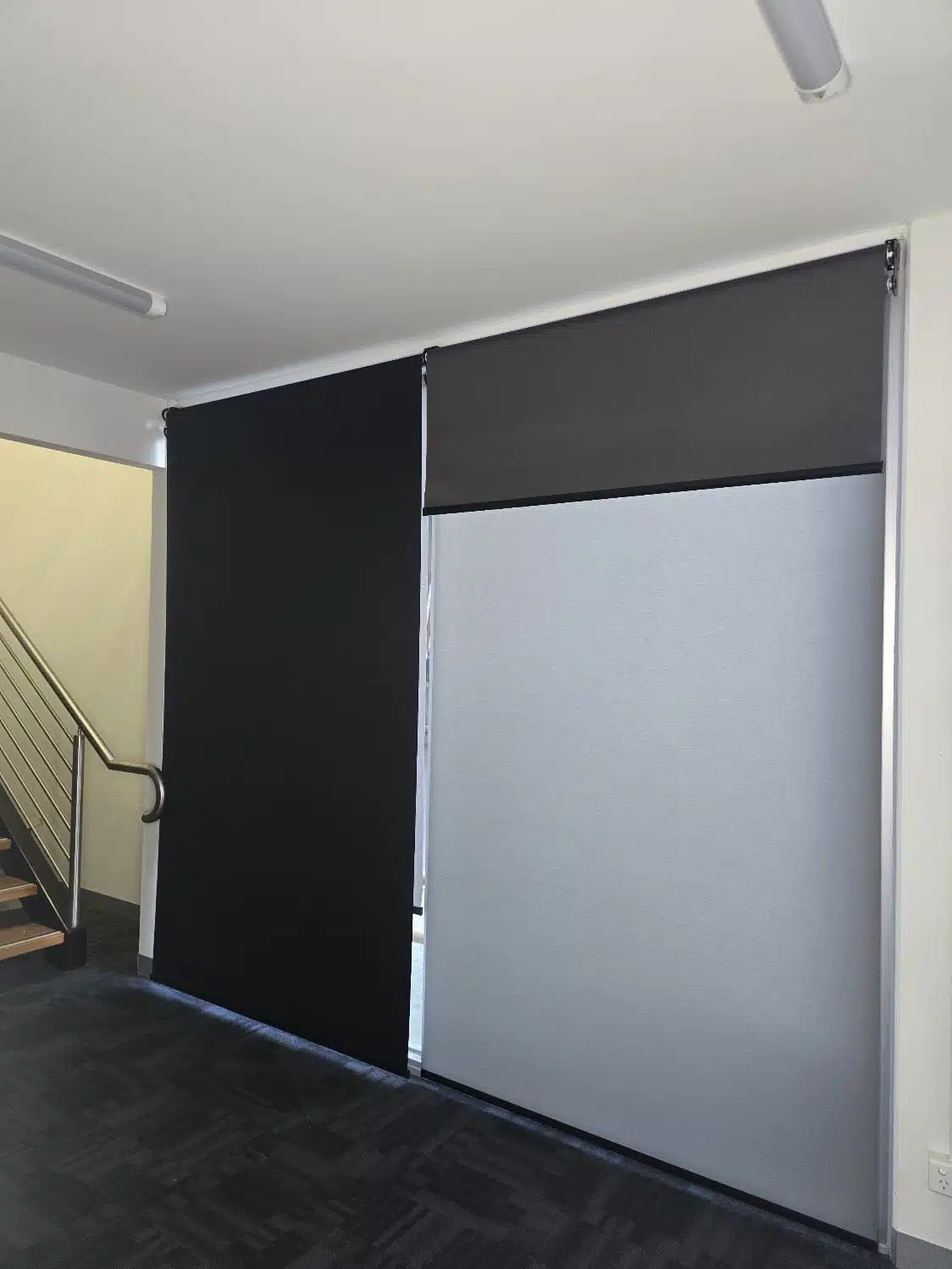 Black and grey roller blinds fitted to full-height office windows