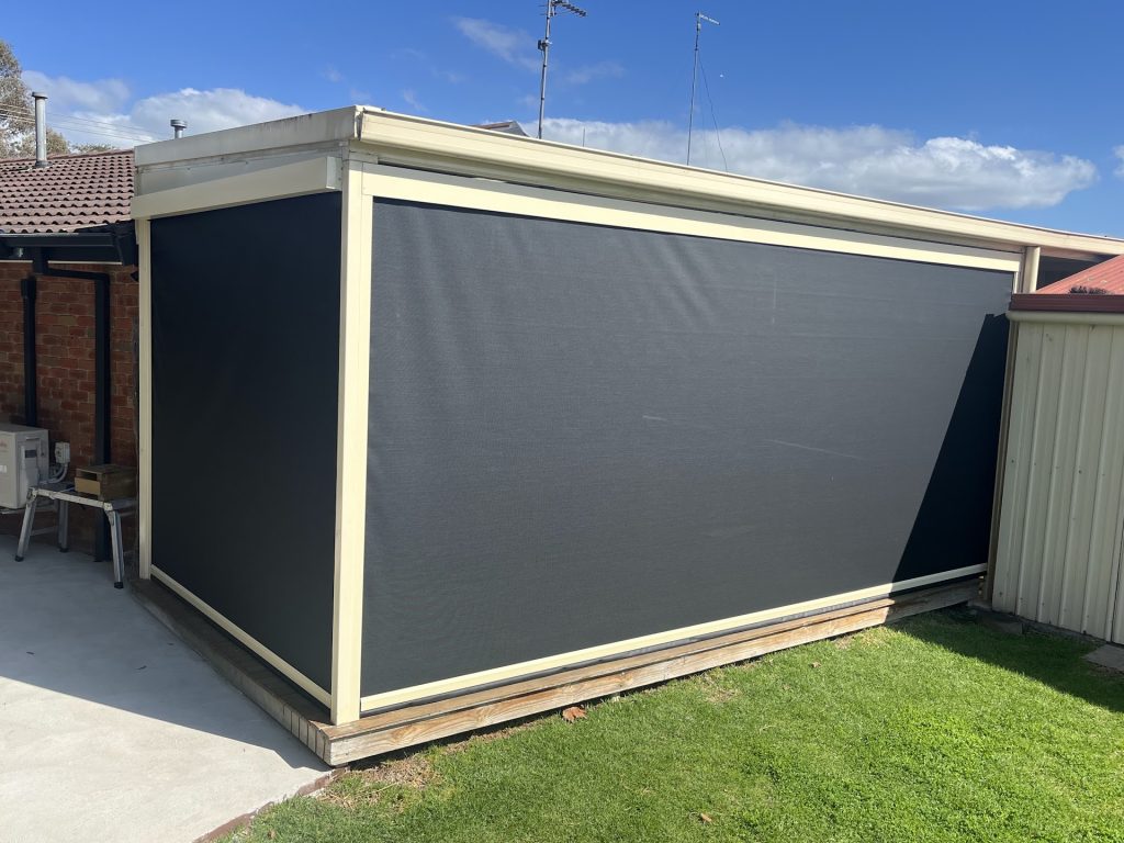Dark outdoor blinds enclosing the sides of a covered patio