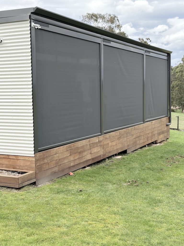 Outdoor blinds enclosing a timber deck beside a home