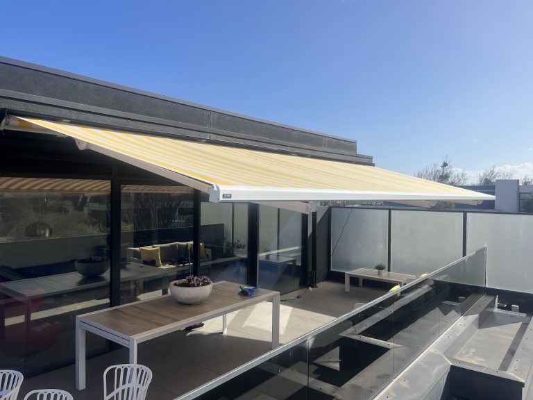 Yellow and white striped Siena folding arm awning extended over a terrace